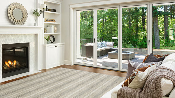 Tan-and-white striped flatweave rug with fireplace, white built-in cabinet and glass sliding doors with view of patio