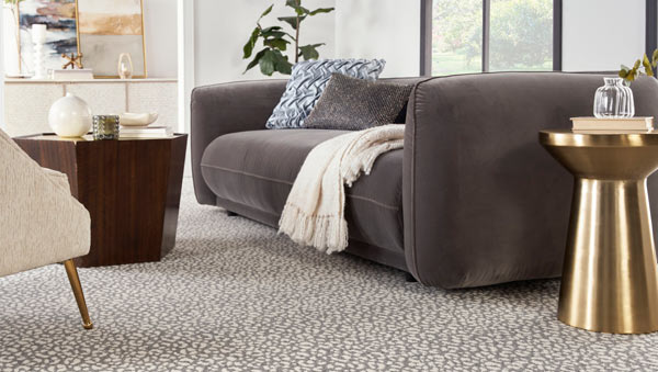 Gray and cream leopard-patterned rug with gray couch and gold end table