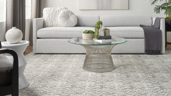 gray and white tiger-patterned rug with white couch, glass coffee table, and gray curtains